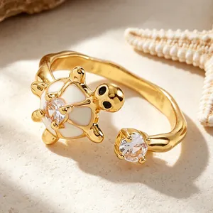 Primer plano detallado de un anillo de tortuga dorado con esmalte blanco y circón