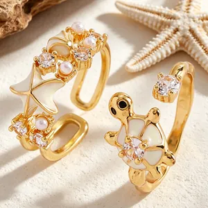 Primer plano de elegantes anillos dorados con estrella de mar tortuga y circonitas