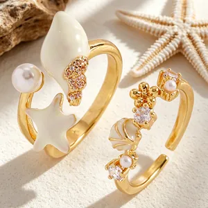 Vista detallada de anillos dorados de temática marina con conchas, estrellas y perlas.