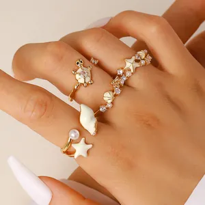 Detalle de cerca de anillos abiertos dorados con motivos de playa estrella de mar y caracola