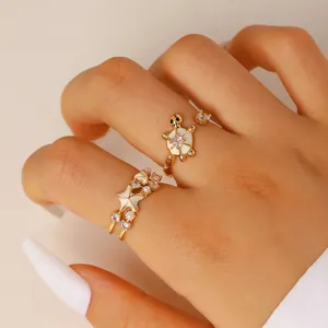 Primer plano de anillos de playa dorados con tortuga y estrella de mar esmaltadas en una mano