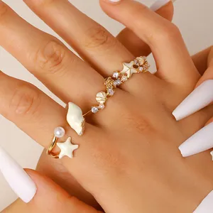 Detalle de anillo abierto estilo playa con caracola, estrella de mar y piedras CZ brillantes.