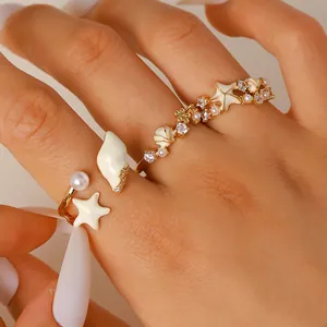 Detalle de anillos dorados de temática marina con conchas estrellas de mar y circón