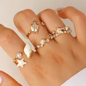 Primer plano detallado de anillos de playa dorados con estrellas de mar y esmalte blanco