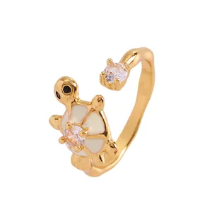 Primer plano de un anillo de tortuga dorado con esmalte blanco y circonitas