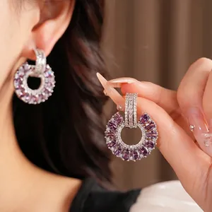 Elegantes pendientes redondos de plata con circonitas púrpuras brillantes y diseño hueco