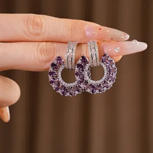 Elegantes pendientes de plata con circonita morada en un diseño circular calado.