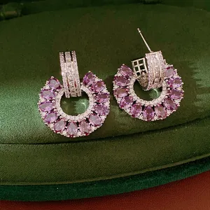 Detalle de pendientes circulares huecos de plata con circonitas púrpuras y transparentes.