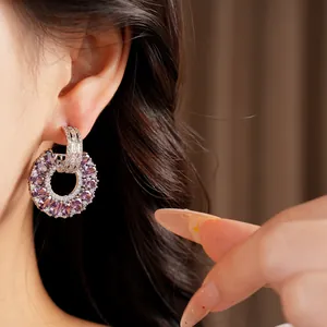 Detalle elegante de pendientes de aro con circonitas moradas y blancas en modelo