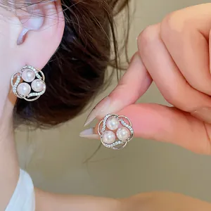 Macro view of elegant silver flower stud earrings featuring three pearls and pavé zircons