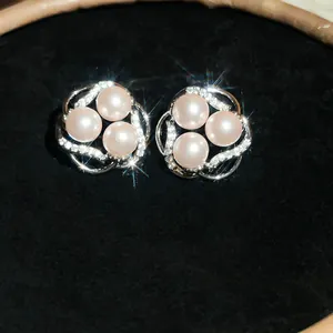 Close-up of elegant pink pearl flower stud earrings with sparkling zircons on black velvet