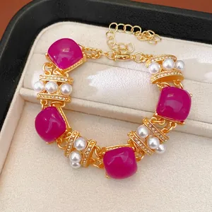 Elegante pulsera vintage dorada con piedras de resina magenta, perlas y diamantes.