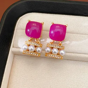 Vista macro detallada de pendientes vintage de resina fucsia con perlas y cristales brillantes.