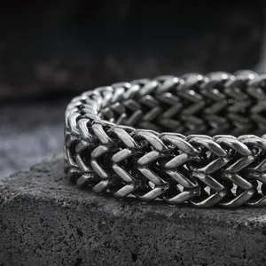 Macro shot of high-density braided stainless steel chain on a dark textured rock surface