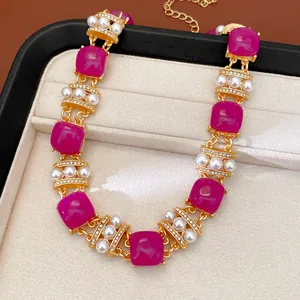 Primer plano de un collar vintage con piedras magenta y perlas en un estuche de joyas