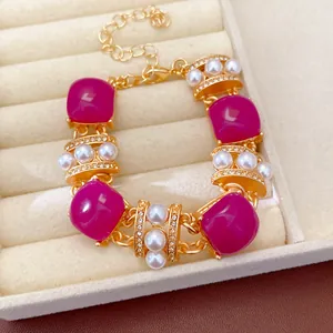 Detalle de cerca de una pulsera vintage dorada con piedras magenta y perlas en un joyero elegante