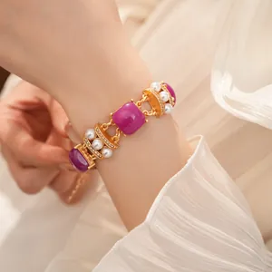 Primer plano de una pulsera vintage dorada con piedras cuadradas moradas y perlas finas