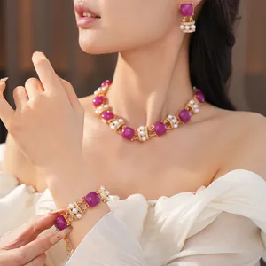 Primer plano de un conjunto de joyas vintage con piedras moradas y perlas blancas.