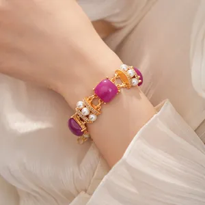 Primer plano de una elegante pulsera dorada de estilo vintage con piedras púrpuras.