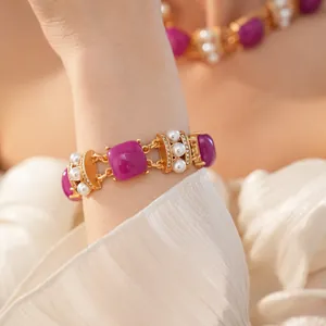 Detalle de primer plano de una pulsera dorada vintage con piedras púrpuras y perlas