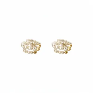 Κομψά σκουλαρίκια ear cuff με πέρλες τριών στρώσεων σε χρυσό, μινιμαλιστικό στυλ.