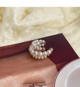 Λεπτομερής όψη του κομψού ear cuff με πολλαπλές στρώσεις λευκών μαργαριταριών και χρυσό.