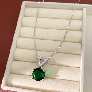 Detailed close-up of V-letter necklace with a large round green gemstone in a jewelry box