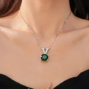 Close-up of V-shaped pendant with round green zircon on a silver chain necklace.