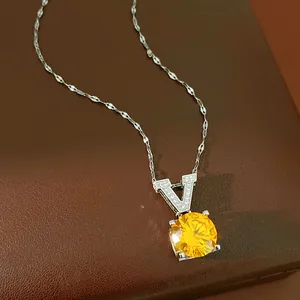 Close-up of elegant V pendant necklace with round faceted yellow zircon gemstone