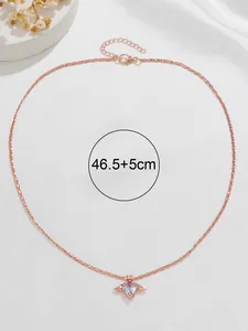 Détail macro du collier cœur en or rose avec ailes d'ange et pierre précieuse mauve