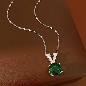 Close-up of elegant V-pendant necklace with a large round green zircon on a brown base