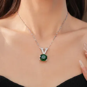 Close-up of a silver necklace with a green round zircon pendant and a V-shaped bail