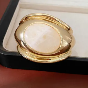 Elegant gold plated open bangle with large oval rose quartz stone in a distorted design.