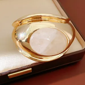 Detailed macro view of the polished gold finish and large oval rose quartz on the bracelet
