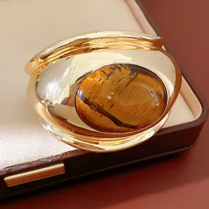 Detailed close-up view of a golden twisted bangle with a large oval tiger's eye
