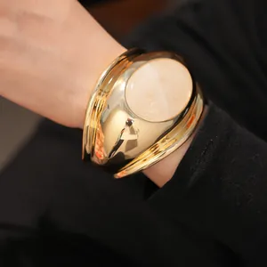 Detail view of chunky gold twisted cuff bracelet featuring a large oval rose quartz stone