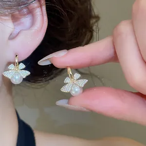 Detail view of elegant French vintage zircon bow earrings with pearls in gold finish.