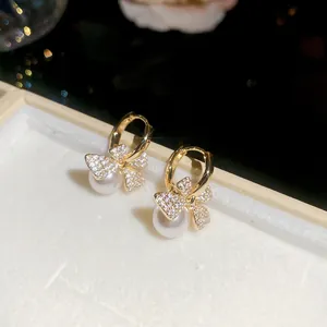 Macro view of French vintage gold bow earrings with zircon stones and elegant white pearls