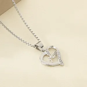 Detailed macro shot of stainless steel heart pendant with Mom engraving and small rhinestones