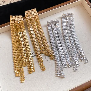 Macro detail of oversized gold and silver metallic mesh tassel earrings on tray