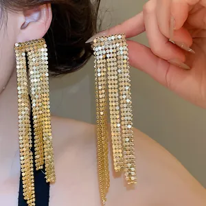 Detailed view of long asymmetric gold tassel earrings for evening party outfits