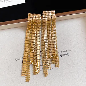 Close-up of gold-plated mesh tassel earrings with shimmering metallic texture.