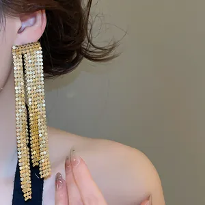 Close-up of gold exaggerated asymmetric mesh tassel earrings for evening banquet events