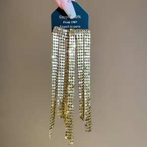 Macro view of elegant oversized gold sequin tassel earrings with asymmetric design.
