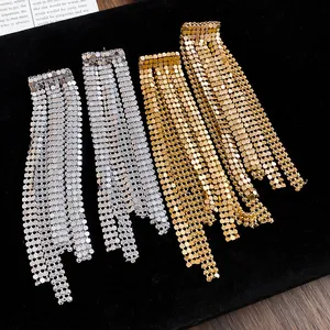 Detail of long asymmetric metal tassel earrings in gold and silver finishes