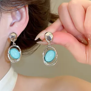 Detail view of vintage oval acrylic pendant earrings with a silver finish worn by a model.