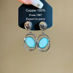 Detailed close-up of French retro oval light blue acrylic pendant earrings with silver finish