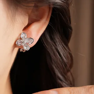 Close-up of sparkling zircon flower ear clip on model's ear, silver-plated finish.