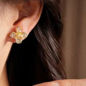 Close-up of gold-plated clover ear clip with sparkling zircons on model's ear.