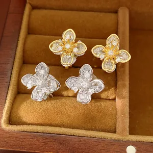Detailed close-up view of zircon clover flower clip earrings in gold and silver finishes